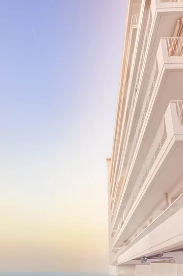 The corner of a white building against a graded blue sky