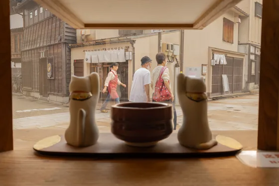 Two ceramic cats and a bowl on a tray, the street beyond in focus